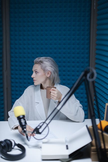 Woman in a recording studio with microphones and headphones, sipping coffee.